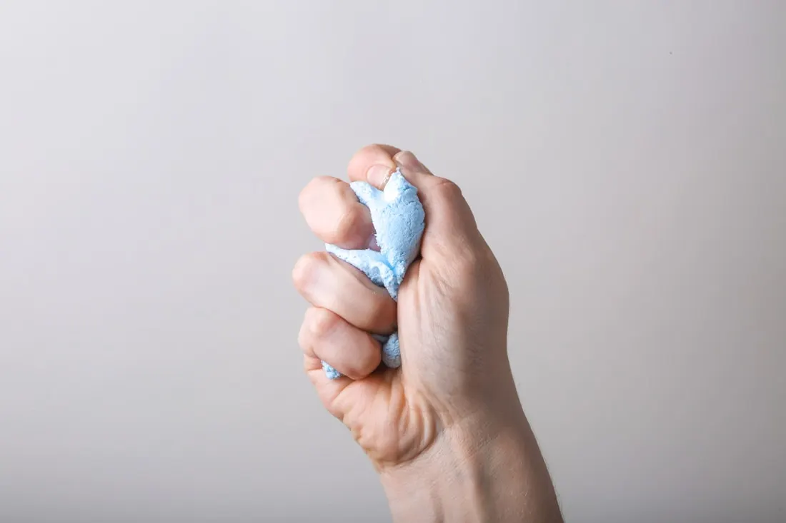 Hand squeezing a piece of stress putty